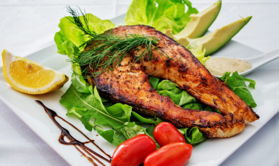 Frisch gebratener Fisch auf Salatbett mit Garnierung auf einem Teller