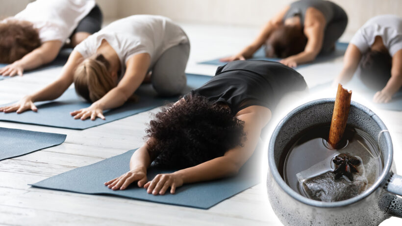 Gruppe von Menschen bei Yoga-Übung auf einer Matte, an der Seite eine Teetasse