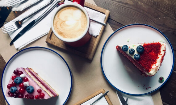 Kaffeetasse mit Milchschaum und zwei Stück Red Velvet-Kuchen angerichtet