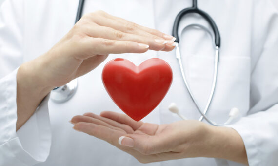 Arzt mit Stethoskop, der das symbolisch ein Herz hält