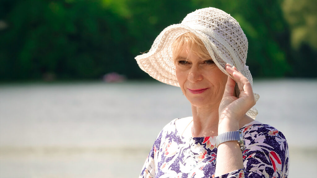 Frau steht am Wasser und schaut in die Ferne