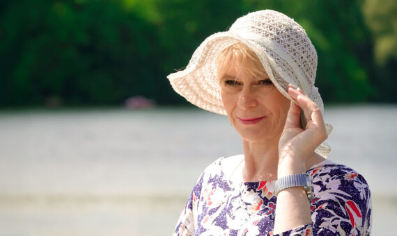 Frau steht am Wasser und schaut in die Ferne